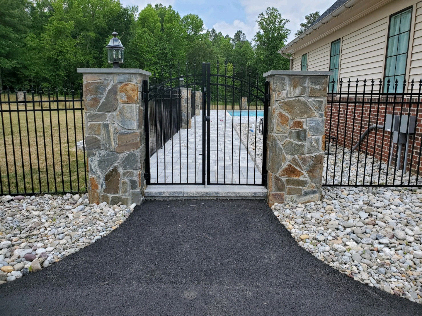 Five foot high, series-b 3-rail aluminum fence with finials and an arched gate on stone columns.