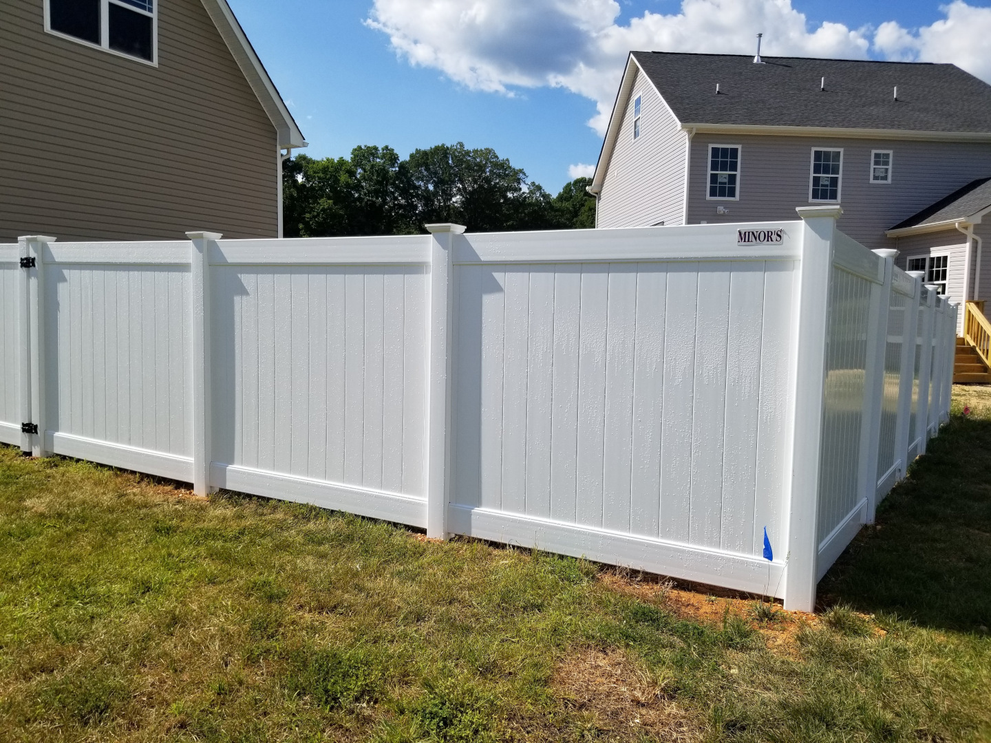 Six foot high white vinyl tongue and groove privacy fence featuring New England post caps.