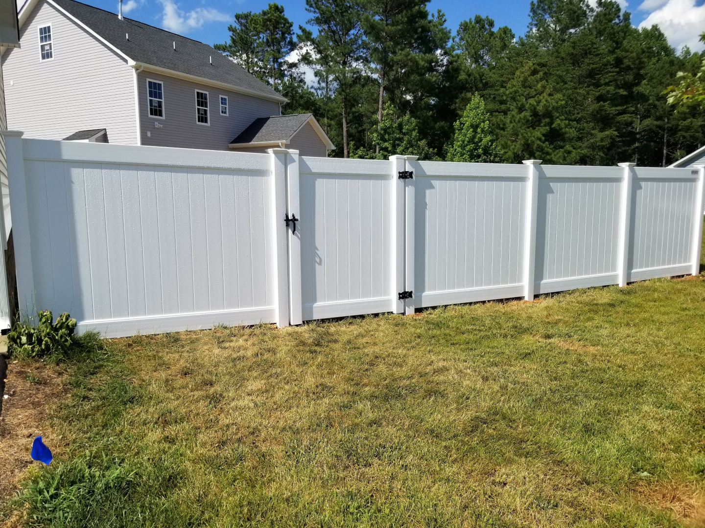 Six foot high white vinyl tongue and groove privacy fence with New England post caps.